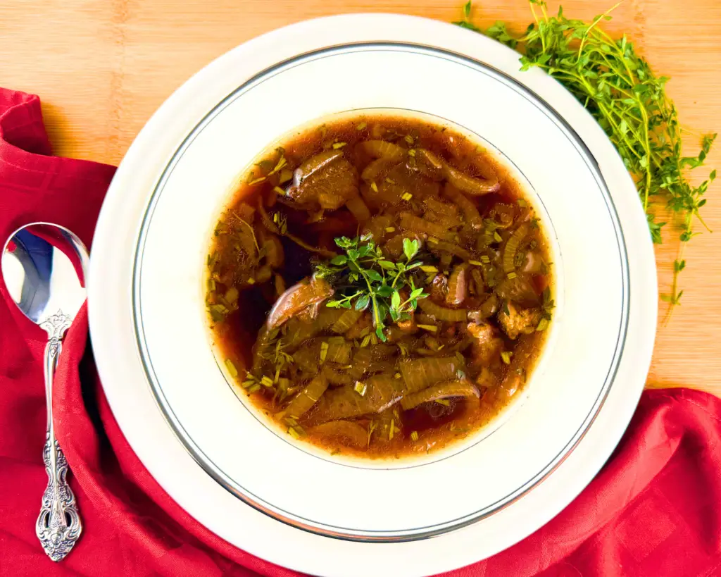 Bowl of Instant Pot Beef Soup with spoon and napkin - garnished with fresh thyme