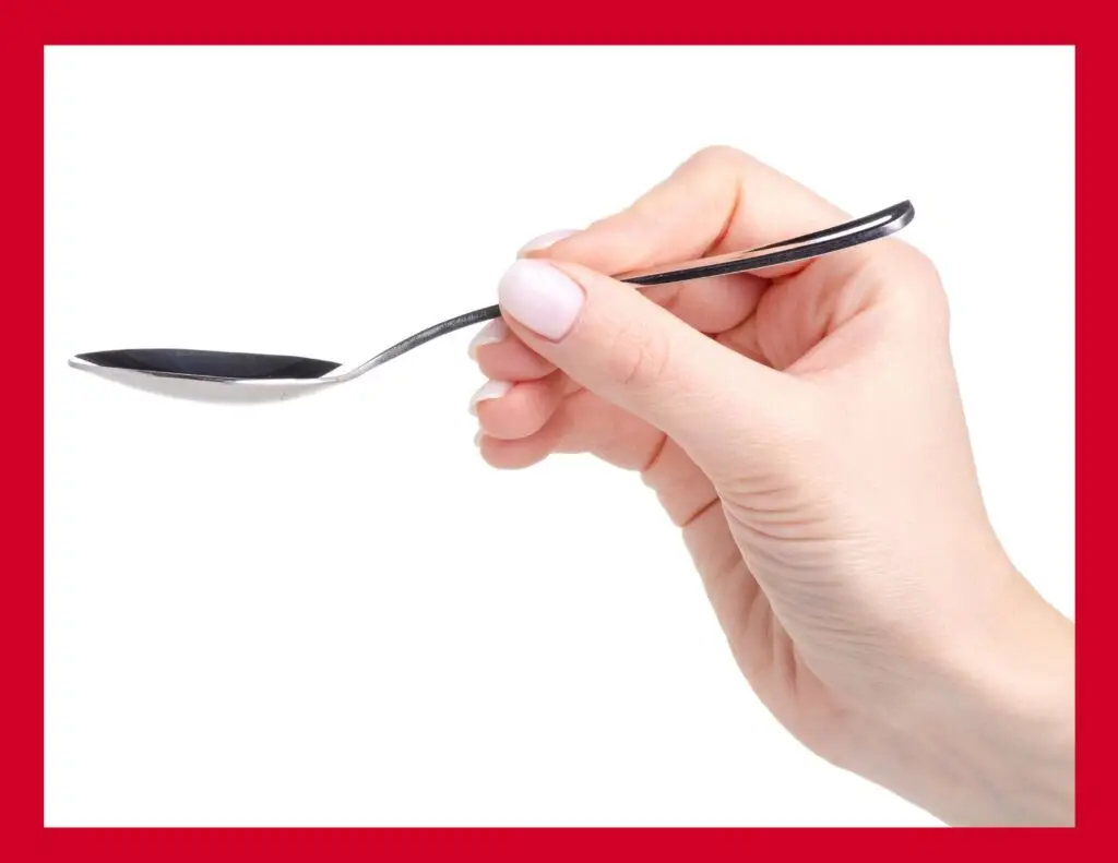 Photo of woman's hand demonstrating the proper way to hold a spoon when eating soup.