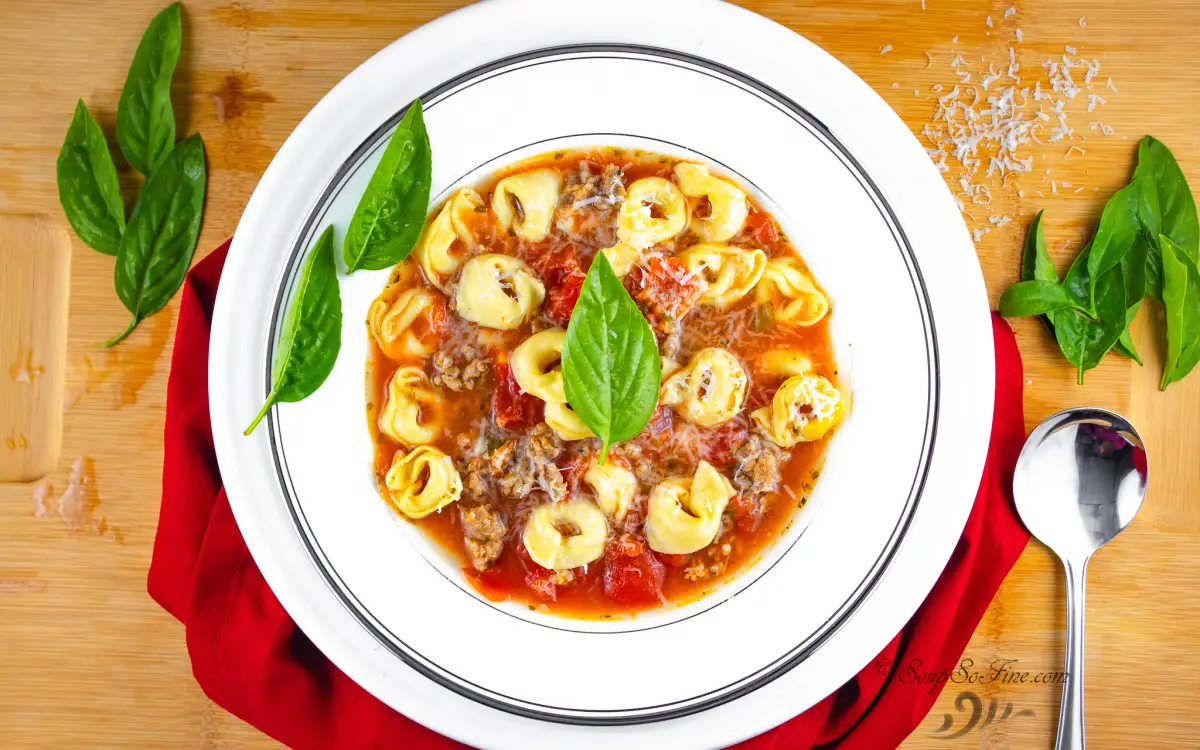 Bowl of Italian Sausage Tortellini Soup with fresh basil leaves garnish